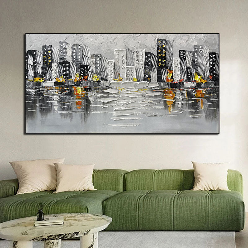 Sentence with the product name: Abstract Art White Pictures Canvas Painting of a cityscape above a green sofa, featuring gray and black buildings with yellow and orange accents, reflected on a water-like surface.