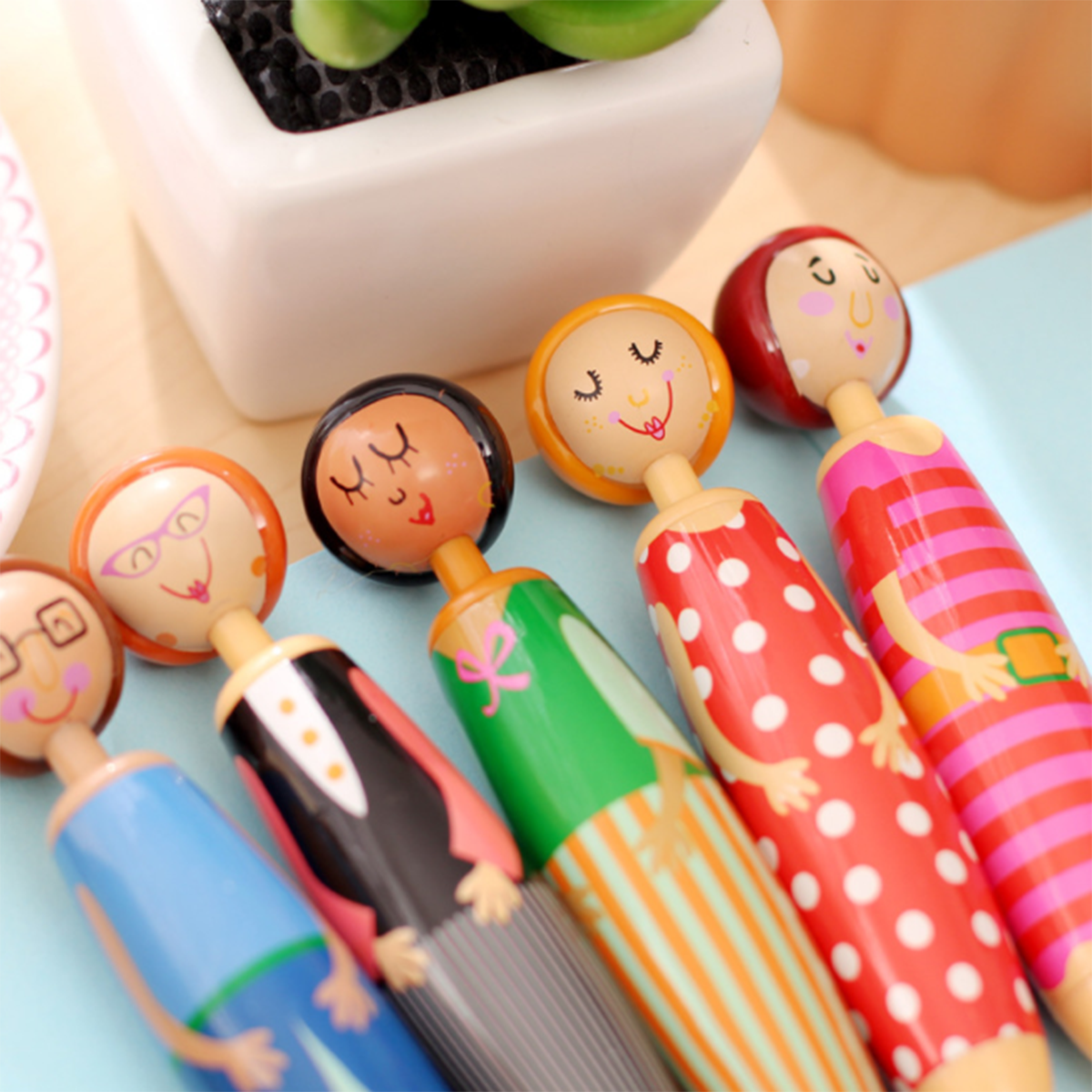 The Pottery Doll Pens Set includes five high-quality ballpoint gel pens, each featuring a wooden top designed as people with different outfits and expressions. This set makes a perfect novelty gift for anyone who loves unique stationery.