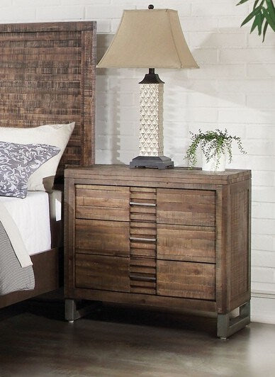 The Andria Nightstand in Reclaimed Oak YJ features metal legs and drawers, creating a transitional feel to your bedroom decor.
