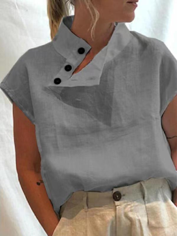 Person wearing a Stylish Blouses Summer Women Cotton Linen Short Sleeve Buttons Solid Shirt in navy blue, paired with light-colored trousers, standing against a plain backdrop.