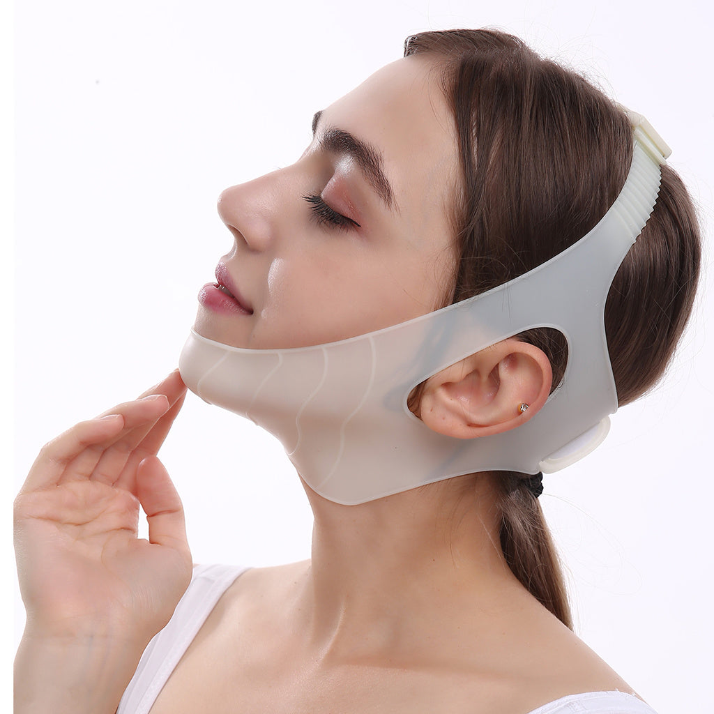 A person wearing a Women Chin Cheek Silicone Face Slimming Bandage Lift Up Belt V Line Face Shaper Facial Anti Wrinkle Strap Skin Care Beauty Tools that covers the chin and wraps around the back of the head. Their hand gently touches the bandage, highlighting its intricate details.