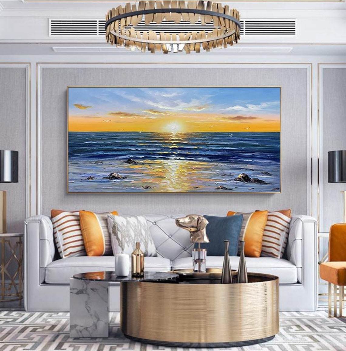 A modern living room with elegant decor featuring a large, colorful Abstract Wall Decor Palette Knife Oil Painting Seascape Picture above a white sofa, accompanied by stylish furniture and a circular centerpiece table.