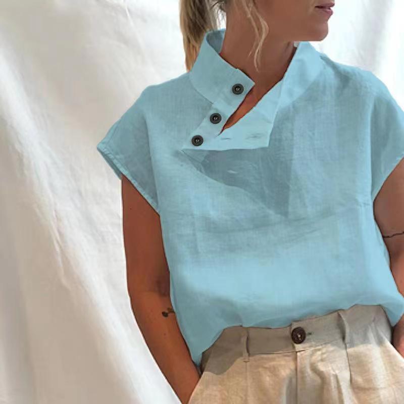 Person wearing a Stylish Blouses Summer Women Cotton Linen Short Sleeve Buttons Solid Shirt in navy blue, paired with light-colored trousers, standing against a plain backdrop.