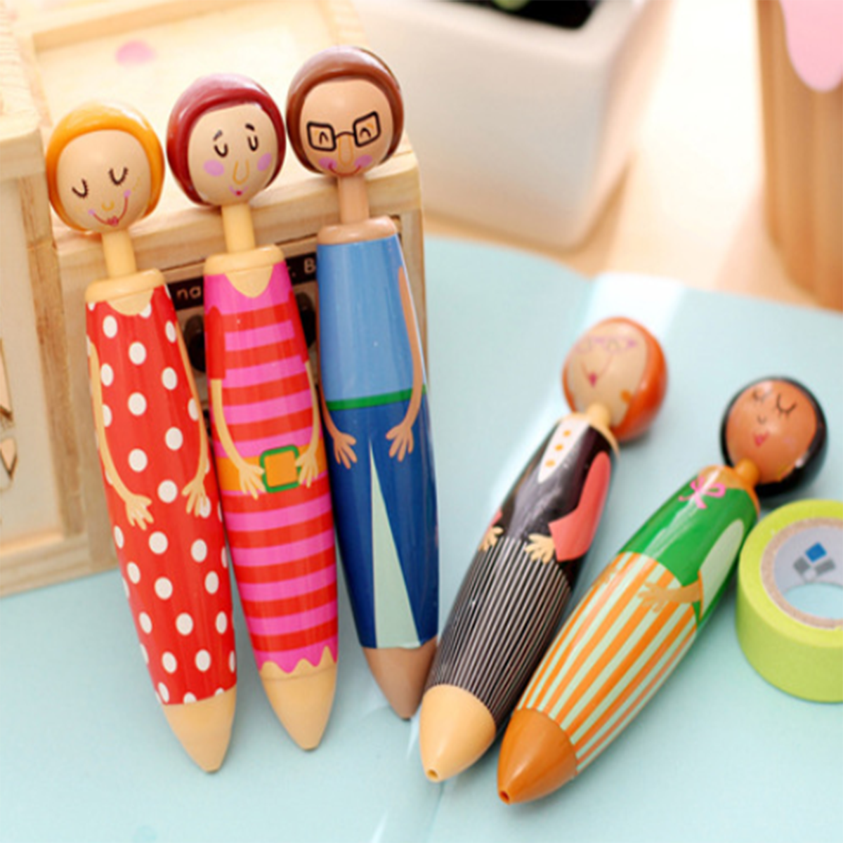 The Pottery Doll Pens Set includes five high-quality ballpoint gel pens, each featuring a wooden top designed as people with different outfits and expressions. This set makes a perfect novelty gift for anyone who loves unique stationery.