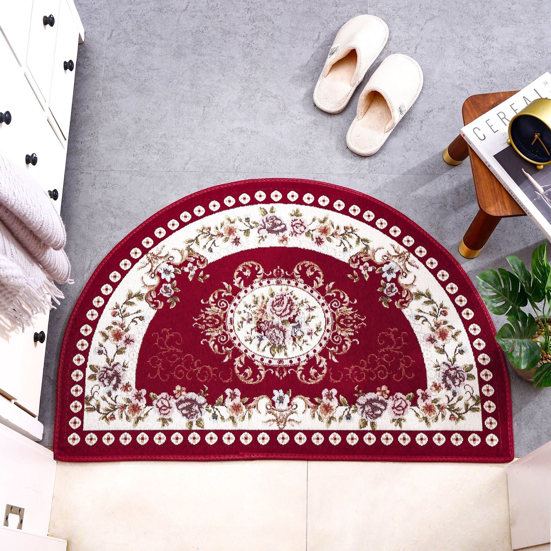 A European Style Semicircle Entrance Carpet with floral designs and a pastel color scheme on a wooden floor, next to a stool and a pair of slippers.