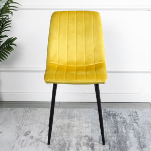 A modern dining room with a white table, four Indoor Velvet Dining Chairs with velvet fabric, and a gray rug, against a blue and white wall with minimalistic artwork.