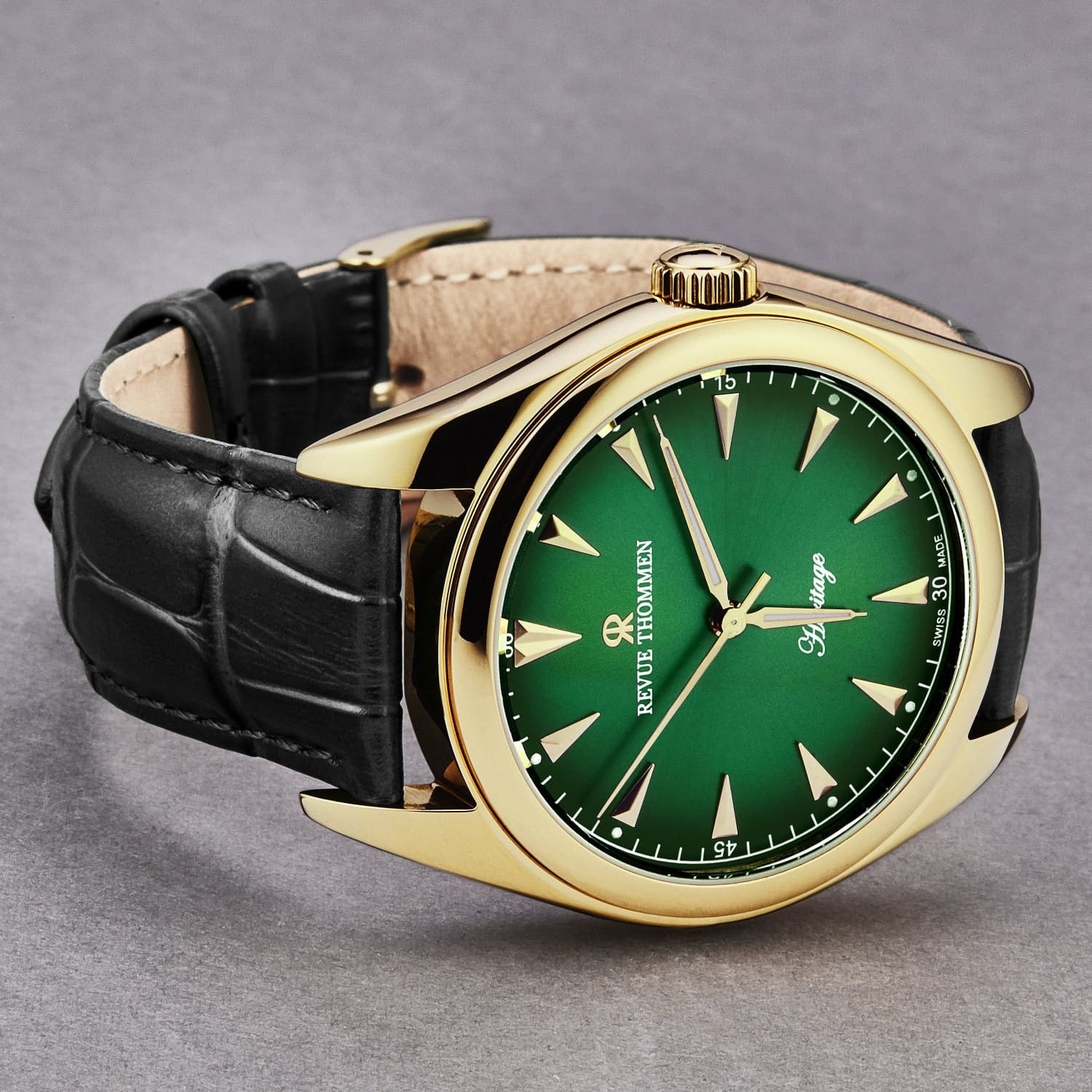 Revue Thommen Men's 'Heritage' Green Dial Black Leather Strap Automatic Watch 21010.2514 features a green dial, gold-toned case, and black leather strap. The dial displays gold hour markers and hands, with "Revue Thommen" and "Heritage" written on it.