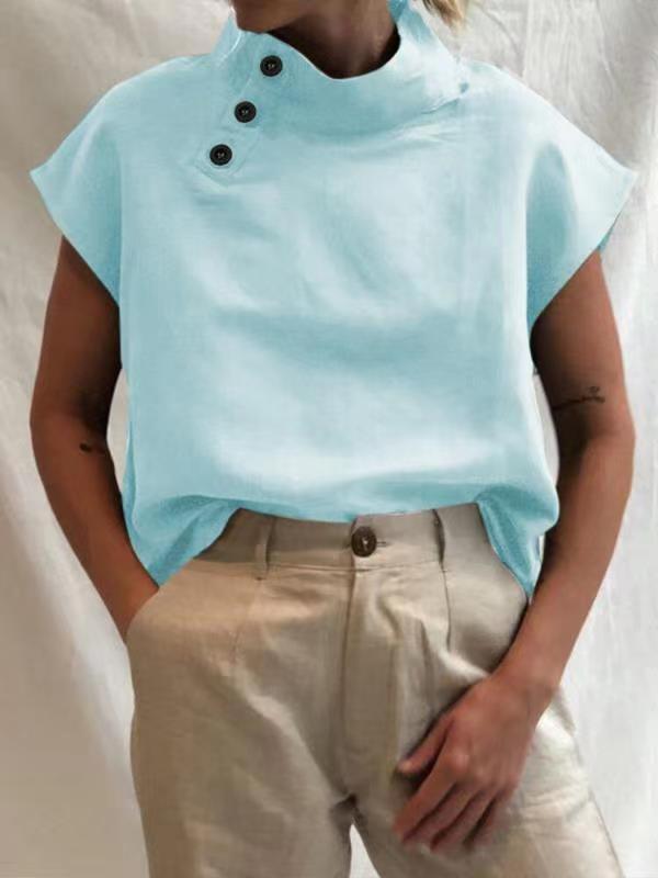 Person wearing a Stylish Blouses Summer Women Cotton Linen Short Sleeve Buttons Solid Shirt in navy blue, paired with light-colored trousers, standing against a plain backdrop.