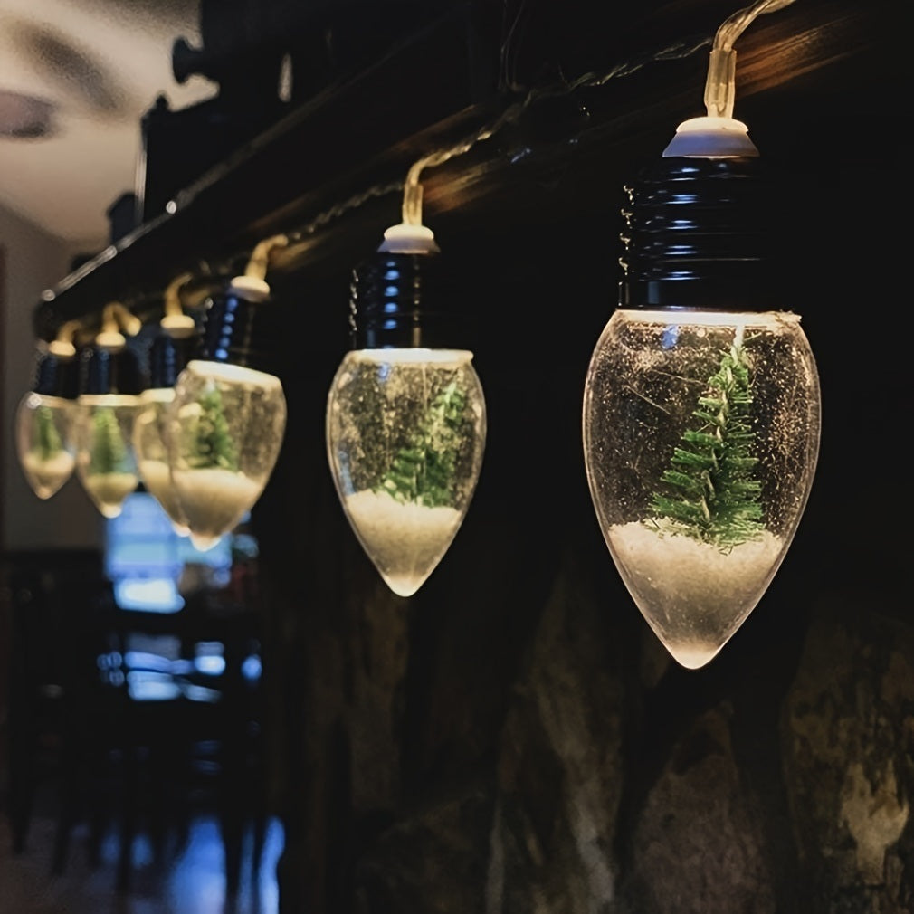 Miniature Christmas Trees encased in clear, teardrop-shaped light bulbs, illuminated by battery-powered lights and hanging from a dark ceiling.