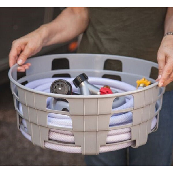 A woman holding a basket full of Stromberg HC-75 Hose Caddy Water Hose Caddy and tools that stores hose accessories.